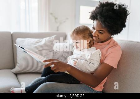 baby-sitter avec bébé lisant un livre Banque D'Images