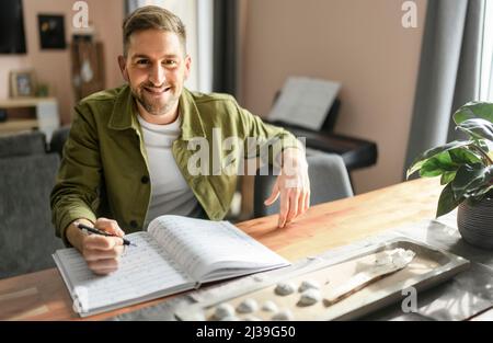 les hommes s'assoient sur une table de cuisine avec une feuille de musique Banque D'Images