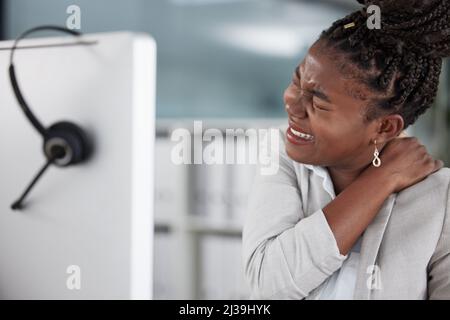 Ne laissez pas votre douleur de dos pour obtenir le meilleur de vous. Photo d'une jeune femme agent de centre d'appels souffrant de douleurs dorsales dans un bureau au travail. Banque D'Images