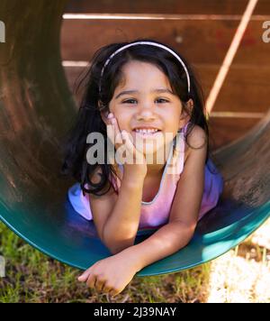 Ici pour rendre un peu de soleil dans votre vie avec son adorable sourire. Photo d'une adorable petite fille qui passe du temps dehors. Banque D'Images