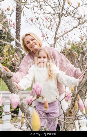 Maman et fille dans le parc avec un magnolia en fleurs. Banque D'Images