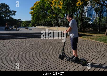 Un homme hispanique senior qui a conduit son scooter électrique dans la ville un matin ensoleillé. Concepts de vie urbaine active, de mobilité moderne et de transp. Écologique Banque D'Images