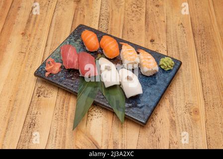 Plateau à sushis nigiri assorti avec thon rouge, saumon norvégien, boulettes de riz blanc, feuilles de banane, babeurre avec truffe et crevettes cuites, gingembre et Banque D'Images
