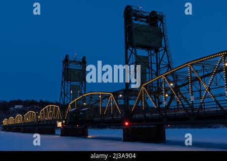 Le pont historique qui traverse la rivière Sainte Croix à Stillwater, Minnesota, vu au crépuscule en hiver avec des lumières de vacances. Banque D'Images