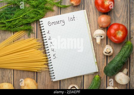 Liste d'achats vierge sur papier avec légumes sur table en bois Banque D'Images