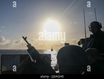 MER DES PHILIPPINES (20 mars 2022) le destroyer de missile guidé de classe Arleigh Burke USS Milius (DDG 69), arrière-plan, tire sur une cible simulée en naviguant en formation avec le destroyer de missile guidé de classe Arleigh Burke USS Higgins (DDG 76), au premier plan. Higgins est affecté au commandant de la Force opérationnelle (CTF) 71/Destroyer Squadron (DESRON) 15, le plus grand DESRON déployé à l’avant de la Marine et la principale force de surface de la flotte américaine 7th. (É.-U. Photo de la marine par le spécialiste des communications de masse 2nd classe Arthur Rosen) Banque D'Images