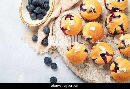 Muffin aux bleuets sur une assiette en bois. Baies fraîches et pâtisseries sucrées sur fond blanc, vue du dessus. Banque D'Images