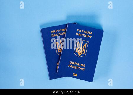 Deux passeports biométriques de citoyens ukrainiens sur fond bleu. Le concept de migration des Ukrainiens Banque D'Images