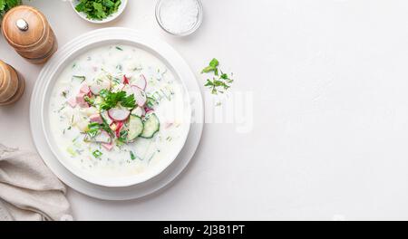 Okroshka, été, soupe froide avec légumes, herbes fraîches et kéfir. Vue de dessus, espace de copie. Banque D'Images
