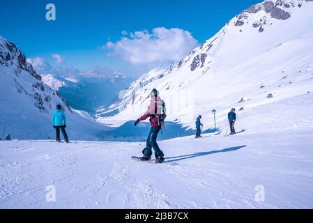 Snowboarders et skieurs se tenant sur une pente de montagne enneigée à la station d'hiver Banque D'Images