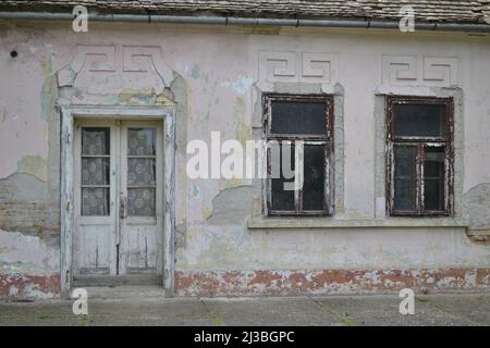 Une vieille porte en bois et une fenêtre cassée avec un cadre en bois blanc décoratif antique délabré, placé sur le mur de la maison familiale. Banque D'Images