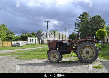 Ancien type de tracteur agricole avec remorque garée dans le village. Banque D'Images