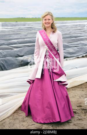 Beelitz, Allemagne. 07th avril 2022. La nouvelle reine Joelina se dresse sur un champ d'asperges de la ferme de l'agriculteur Josef Jakobs pendant le taraudage traditionnel des asperges. Au début de la saison des asperges, les légumes sont récoltés en premier, cultivés sous feuille. L'enfant de 17 ans a été couronné reine par l'Association Beelitz Asparagus. Crédit : Soeren Stache/dpa/Alay Live News Banque D'Images