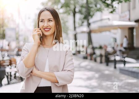 une jeune femme attrayante communique sur un smartphone dans une rue urbaine. Banque D'Images
