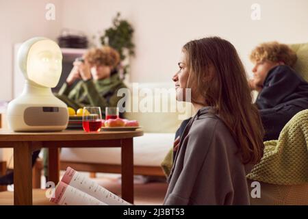 Fille faisant ses devoirs avec un assistant vocal robotique Banque D'Images