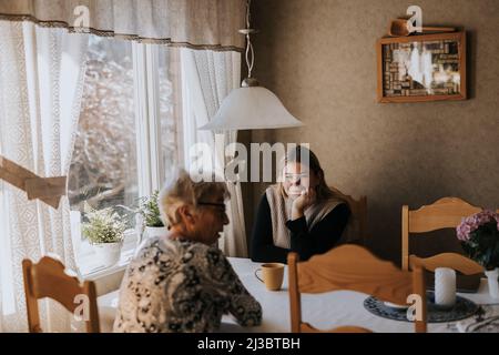 Grand-mère et petite-fille adulte assis à la table et prenant le thé Banque D'Images