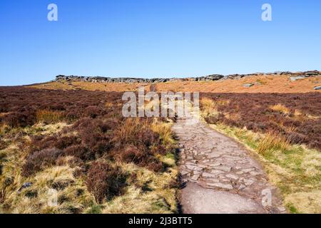 Le chemin étroit couvert de pierre à aiguiser traverse la lande sèche et jusqu'au sommet de Stanage Edge dans le Derbyshire. Banque D'Images