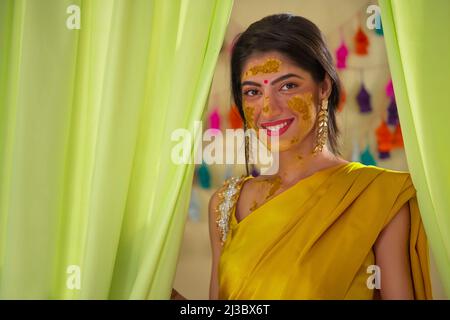 Portrait d'une mariée indienne heureuse avec pâte curcuma sur le visage Banque D'Images