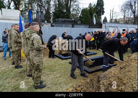 Lviv, Ukraine. 06th avril 2022. Les gens couvrent les tombes des soldats avec du sol lors de la cérémonie funéraire de 3 soldats ukrainiens. Service funéraire de trois soldats ukrainiens, Liubomyr Gudzelyak, le sergent Vyacheslav Ubiyvovk et Ruslan Koval, tués par les forces russes dans le cadre de l'invasion de l'Ukraine par la Russie. Crédit : SOPA Images Limited/Alamy Live News Banque D'Images