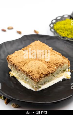 Baklava froide sur fond blanc. Le baklava froid préparé avec du lait et de la pistache est très populaire. Cuisine méditerranéenne traditionnelle. Fermer Banque D'Images