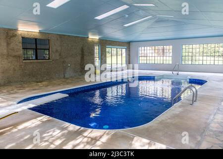 Grande piscine intérieure avec beaucoup de lumière naturelle provenant de grandes fenêtres dans un atrium Banque D'Images