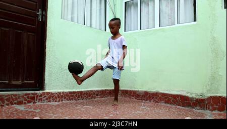 Enfant africain jouant avec le ballon, enfant noir de jeune garçon joue le sport par lui-même Banque D'Images