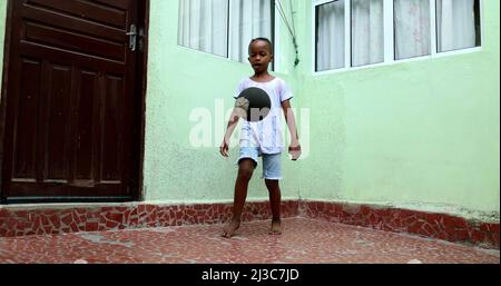 Enfant africain jouant avec le ballon, enfant noir de jeune garçon joue le sport par lui-même Banque D'Images