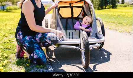 Belle jeune famille avec bébé dans une poussette de jogging en dehors de la saison d'été Banque D'Images