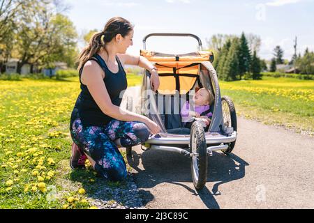 Belle jeune famille avec bébé dans une poussette de jogging en dehors de la saison d'été Banque D'Images