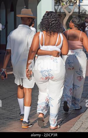 Le Cap, Afrique du Sud. 2022. Vue arrière de deux dames et un homme mince marchant sur le front de mer à Cape Town. Banque D'Images