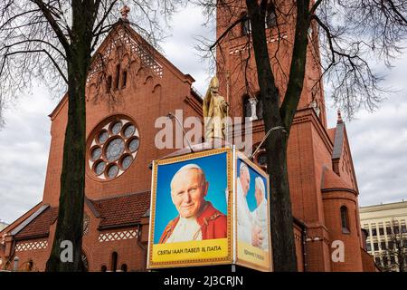 Minsk, Bélarus, 04.11.21. Saint Jean-Paul II statue d'or du Pape devant l'Église des Saints Simon et Helena (Église Rouge) avec le Pape Benoît XVI et Banque D'Images