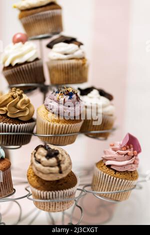 Assortiment de petits gâteaux savoureux placés sur un support en métal sur la table de la boulangerie Banque D'Images