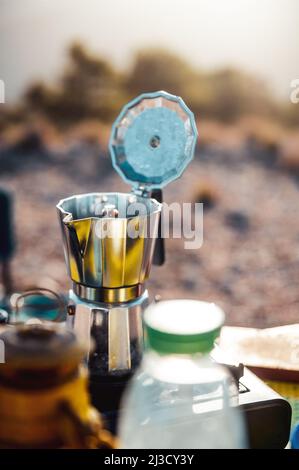 Pot en métal avec couvercle ouvert placé sur le poêle à gaz portable pour préparer du café frais aromatique dans le camping Banque D'Images