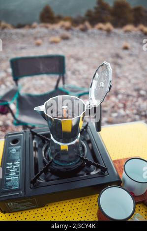 Pot en métal avec couvercle ouvert placé sur le poêle à gaz portable pour préparer du café frais aromatique dans le camping Banque D'Images