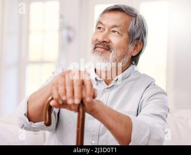 Je suis impatient d'aujourd'hui. Photo d'un homme âgé assis à la maison avec un bâton de marche en bois. Banque D'Images