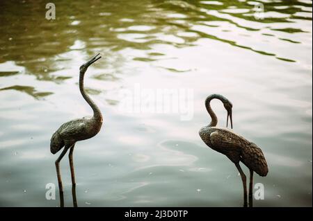 Concept d'amour éternel. Deux statues en pierre de flamant dans l'étang Banque D'Images