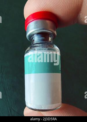Une petite bouteille de médecine liquide avec un endroit vide pour une inscription est tenue par une personne avec deux doigts de près Banque D'Images