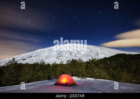 Tente illuminée sous le mont Etna d'hiver et les pistes étoiles, la Sicile Banque D'Images