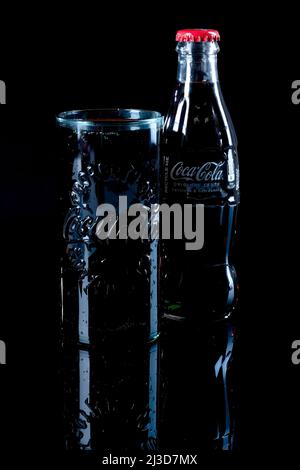 HELSINGBORG, SUÈDE - 06 AVRIL 2022 : une photo en studio d'un verre de coca cola à côté de la célèbre bouteille en verre. Banque D'Images