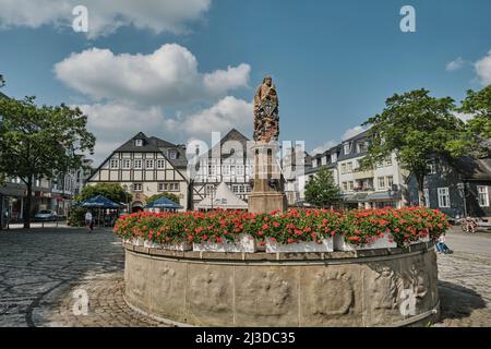 Ancienne fontaine avec sculpture dans le centre-ville de Brilon avec des maisons médiévales au cadre de l'espace en arrière-plan Banque D'Images