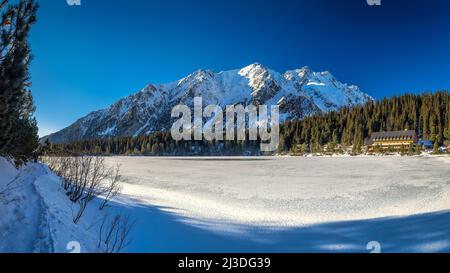 Vue panoramique sur le paysage de montagne avec le tarn gelé en hiver. Le lac de Popradske pleso dans le parc national des Hautes Tatras, Slovaquie, Europe. Banque D'Images