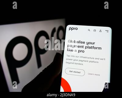 Personne tenant smartphone avec le site Web de la société britannique fintech PPRO Financial Ltd. À l'écran avec logo. Concentrez-vous sur le centre de l'écran du téléphone. Banque D'Images