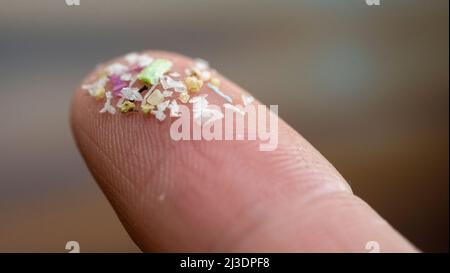 Gros plan de microplastiques sur les doigts humains. Concept de pollution de l'eau et de réchauffement de la planète. L'idée du changement climatique. Banque D'Images