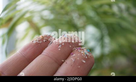 Gros plan de microplastiques sur les doigts humains. Concept de pollution de l'eau et de réchauffement de la planète. L'idée du changement climatique. Banque D'Images