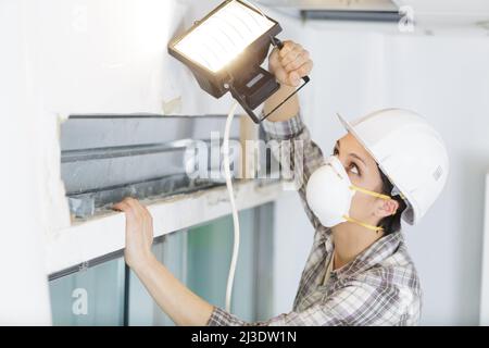 jeune femme utilisant une lumière pour voir des dommages Banque D'Images