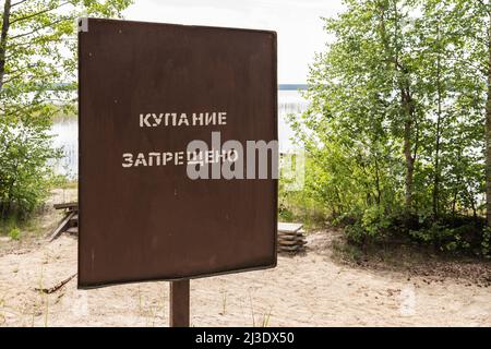 Pas de natation, bannière en métal rouillé avec texte russe monté sur une côte de lac Banque D'Images