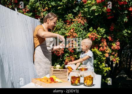 Mise en conserve des légumes du jardin, conservation des tomates, des poivrons, des légumes courgettes. Aliments fermentés. La mère et l'enfant de famille en conserve des légumes dans le Banque D'Images