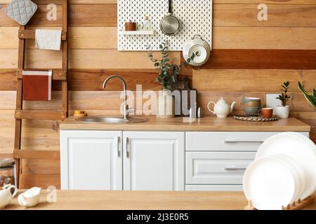 Assiettes sur table et comptoir de cuisine avec évier près du mur en bois Banque D'Images