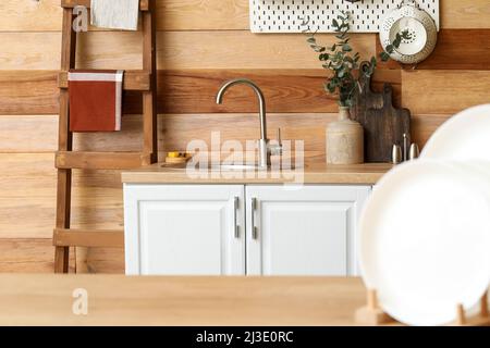 Assiettes sur table et comptoir de cuisine avec évier près du mur en bois Banque D'Images