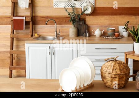 Assiettes sur table et comptoir de cuisine avec évier près du mur en bois Banque D'Images